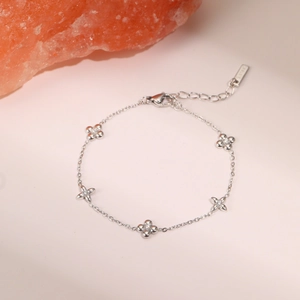 Detailed close-up of a silver stainless steel clover bracelet with zircon studs