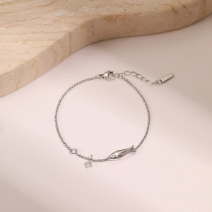 Detailed macro view of silver steel bracelet with fish pendant and zircon stones