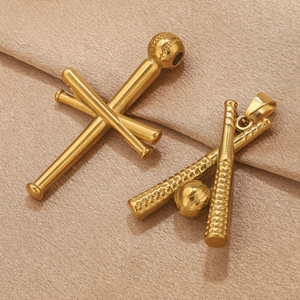 Macro shot of 18k gold plated baseball bat cross pendants on textured fabric