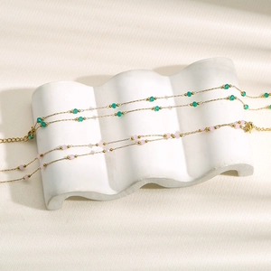 Collares dorados de acero inoxidable con cuentas esmeralda y rosas en soporte blanco