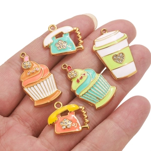 Bunte Emaille-Anhänger mit Retro-Telefon und Cupcake-Motiven in der Hand präsentiert