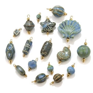 Vista macro de colgantes marinos de cerámica azul con aros de metal chapados en oro