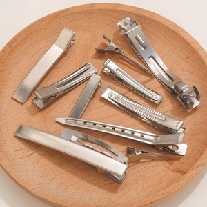 Set of stainless steel hair clips for salon styling on a decorative wooden tray