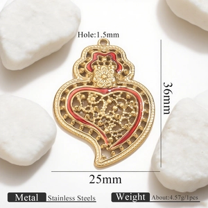 Macro detail of a 36mm heart wing pendant in gold stainless steel and red enamel
