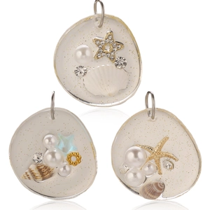 Detail of resin ocean pendants featuring shells, pearls and starfish with gold glitter