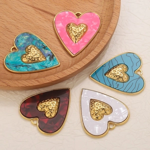 Détail de pendentifs en cœur avec motifs émaillés colorés et finitions dorées