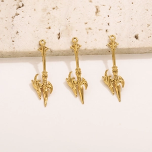 Three golden fantasy spear pendants for DIY jewelry making on white stone background