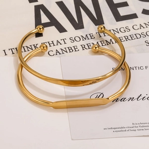 Close-up of gold stainless steel bangle set with engraved love script and ball ends