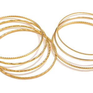 Detalle de brazaletes de titanio dorados apilables con texturas trenzada y martillada