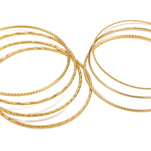 Elegantes pulseras apilables de acero de titanio dorado con acabados texturizados y pulidos
