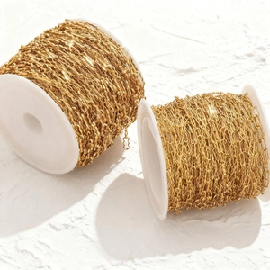Golden wavy stainless steel peanut chain rolls for DIY jewelry making on stone surface