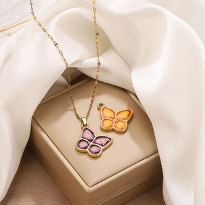Macro detail of gold-edged purple butterfly pendant on an elegant white satin background