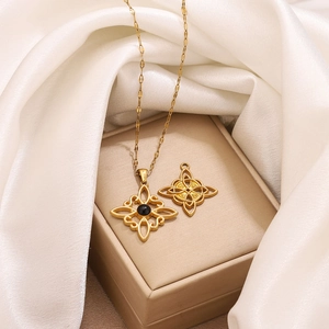 Collar dorado con colgante de nudo celta y cuenta negra sobre fondo de seda