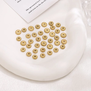 Golden twisted rope spacer beads for DIY jewelry making on white textured tray