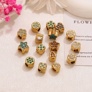 Macro shot of 18K gold-plated clover and star spacer beads with colorful rhinestones on silk