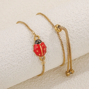 Detail eines verstellbaren goldenen Box-Chain-Armbands mit einem roten Marienkäfer