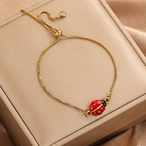 Makroaufnahme von Goldbox-Kettenarmband mit Marienkäfer-Anhänger und Schiebeperle