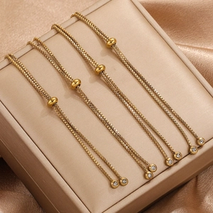Detail von vier goldenen Box-Chain-Armbändern mit Schiebeverschluss auf Seidendisplay