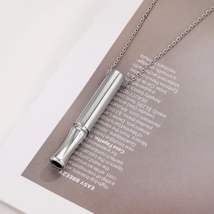 Polished stainless steel mindfulness whistle necklace on a fashion magazine background
