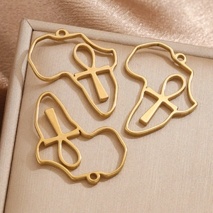 Macro detail of gold stainless steel Africa map and Ankh cross pendants on silk base