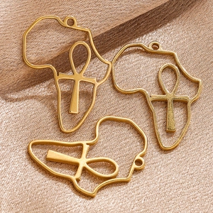 Detailed close-up of golden Africa map pendants with Ankh symbols on silk fabric