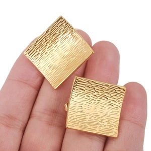 Gros plan de boucles d'oreilles carrées dorées montrant la texture linéaire et le fini