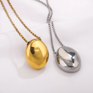 Collane geometriche a goccia minimaliste in oro e argento su sfondo di seta bianca