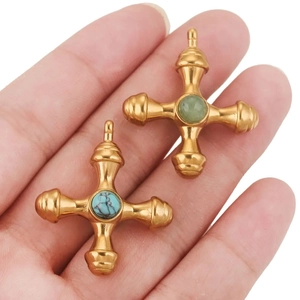 Dettaglio di pendenti a croce in acciaio al titanio placcati oro 18k con turchese