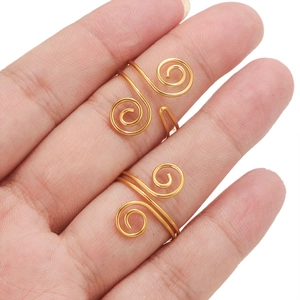 Macro detail of two stacked gold-plated spiral twisted wire rings on a hand