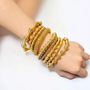 Dettagli di bracciali a strati in acciaio al titanio dorato con trama a filo a spirale