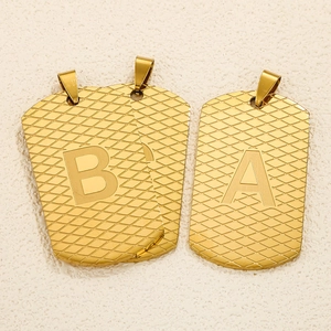 Detail von goldenen Titanstahl-Erkennungsmarken mit Rautenmuster und eingravierten Buchstaben