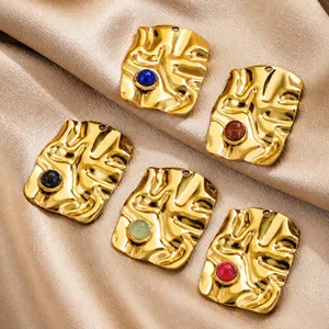 Macro detail of twisted rectangular gold pendants with colorful inset natural stones