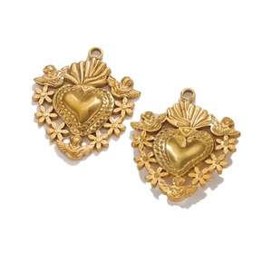 Macro detail of two vintage 18K gold heart charms with floral and angel relief patterns