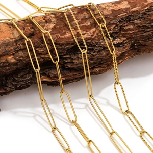 Detail of PVD gold plated stainless steel paperclip and faceted glitter chains on wood