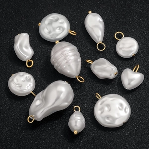 Baroque style irregular pearl pendants with gold rings on black textured surface