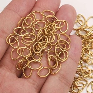 Bulk 18K gold plated oval open jump rings in palm to show miniature DIY jewelry scale