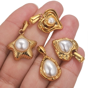 Detailed view of gold star and heart charms with white pearls held in palm
