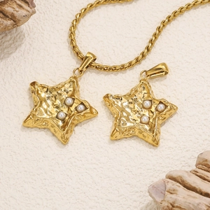 Close-up of golden star pendant with white pearls and hammered texture on twisted chain