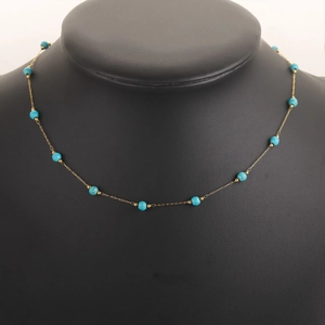 Close-up of 18k gold-plated chain with turquoise beads on a black neck model