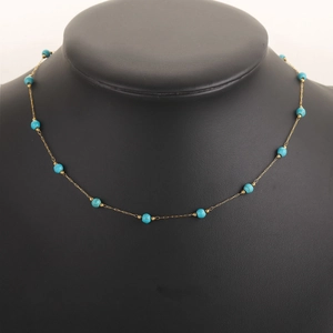 Golden chain necklace with blue turquoise beads displayed on a black neck mannequin