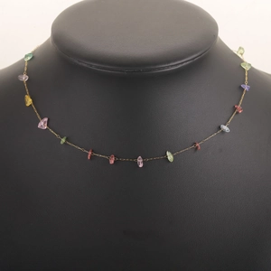 Detail of a thin gold chain necklace featuring irregular colorful natural gemstones
