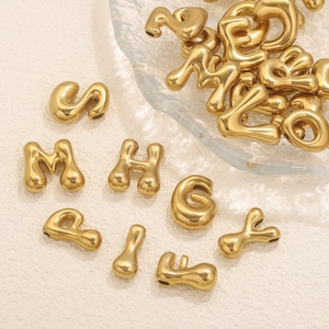 Colgantes de letras 3D dorados para collares DIY presentados en un bol de cristal