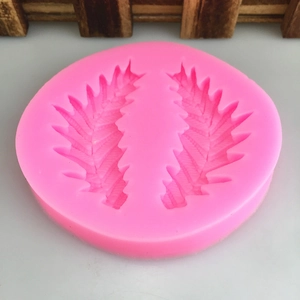 Pink silicone fondant mold featuring detailed symmetrical leaf and feather designs