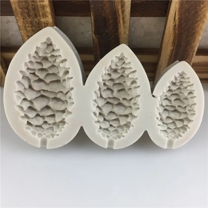 Three pine cone shaped silicone molds for fondant and candles in a natural rustic setting