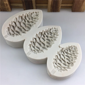 Three-cavity pine cone silicone mold for fondant and soap making on a white surface