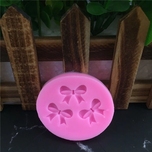 Pink circular silicone mold with detailed bow tie relief patterns for cake decorating