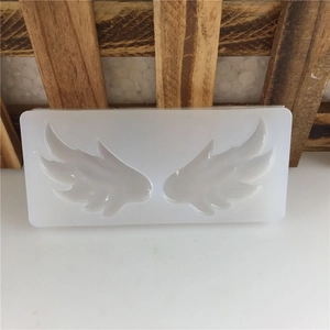 White silicone mold featuring a pair of angel wings with detailed feather textures for baking
