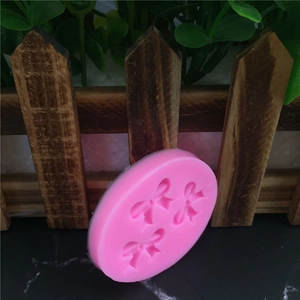 Pink round silicone mold featuring three 3D bow patterns for fondant and cake decorating