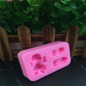 Pink silicone baby angel fondant mold with three cavities on a black marble surface