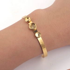 Detailopname van gouden open armband met drie lege bezel-instellingen voor DIY-sieraden